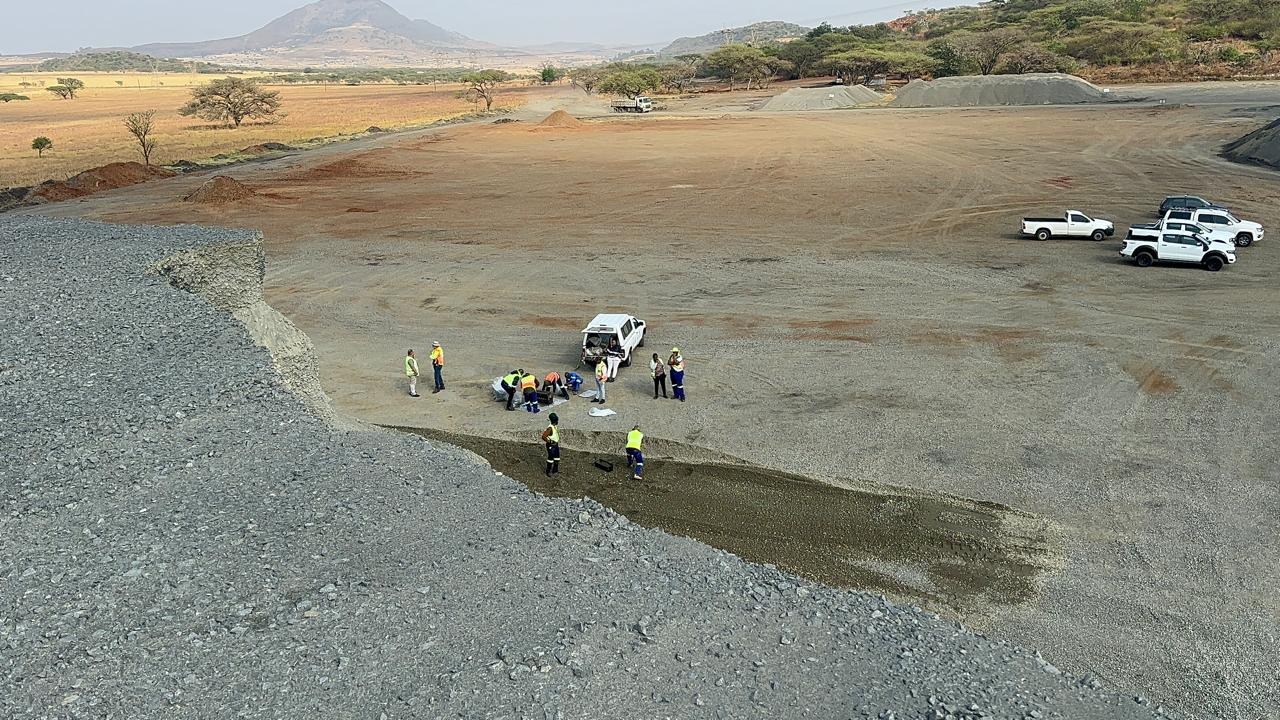Site team setting out works on a prepared platform with stockpiles and bakkies